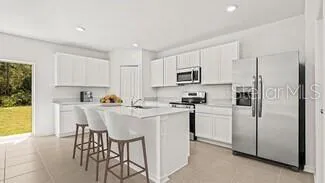 a kitchen with stainless steel appliances a refrigerator a stove a sink a dining table and chairs