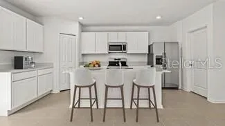 a kitchen with stainless steel appliances kitchen island granite countertop a table chairs refrigerator and microwave