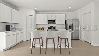 3779 Bergamot Boulevard Lake Alfred, FL 33850 - Photo 19 of 25 a kitchen with stainless steel appliances kitchen island granite countertop a table chairs refrigerator and microwave
