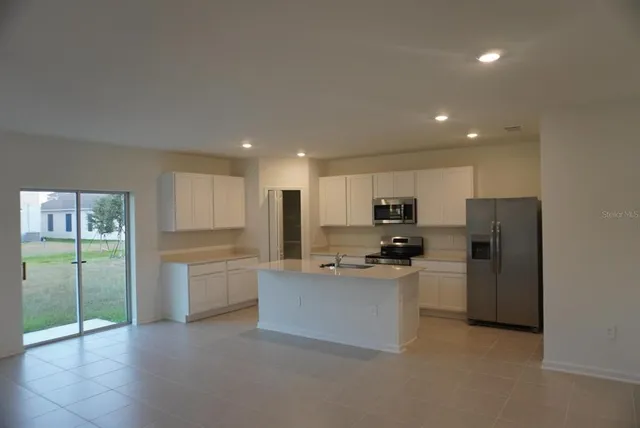 a kitchen with stainless steel appliances kitchen island granite countertop a refrigerator and a stove top oven