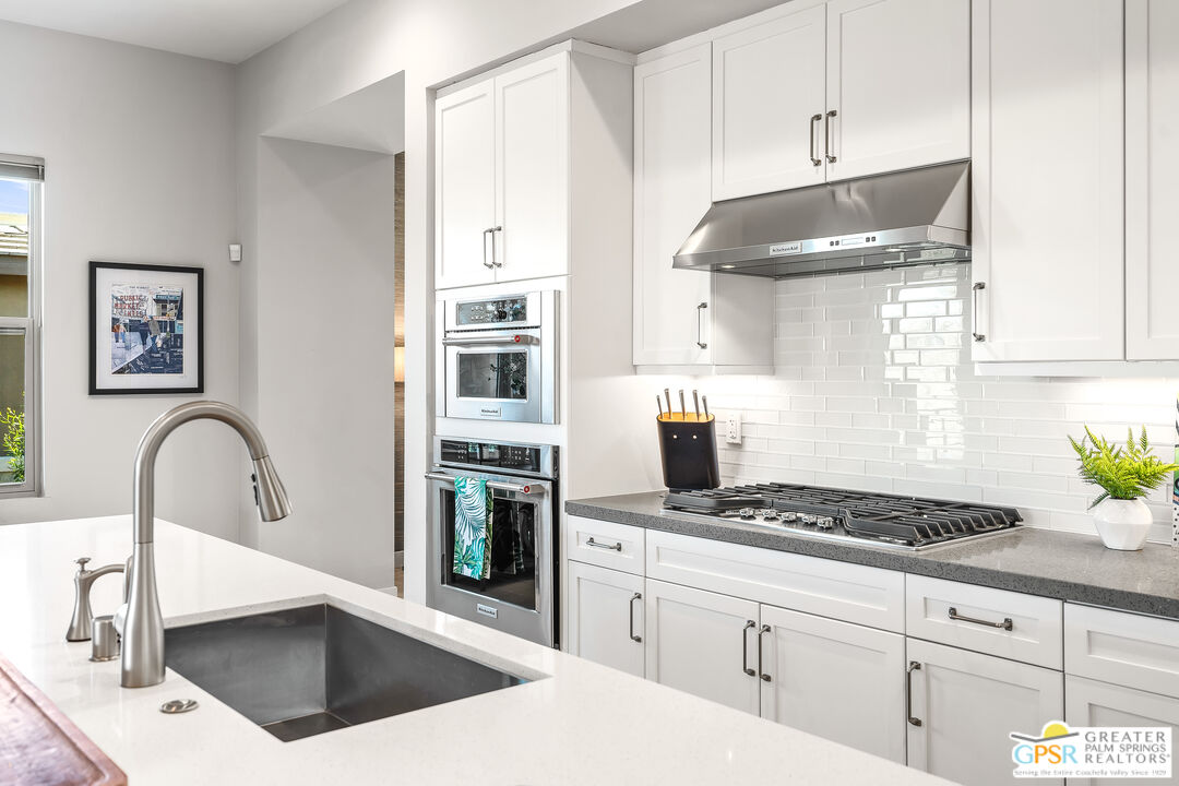 204 Retreat Circle Palm Desert, CA 92260 - Photo 28 of 60 a kitchen with granite countertop a stove a sink and white cabinets
