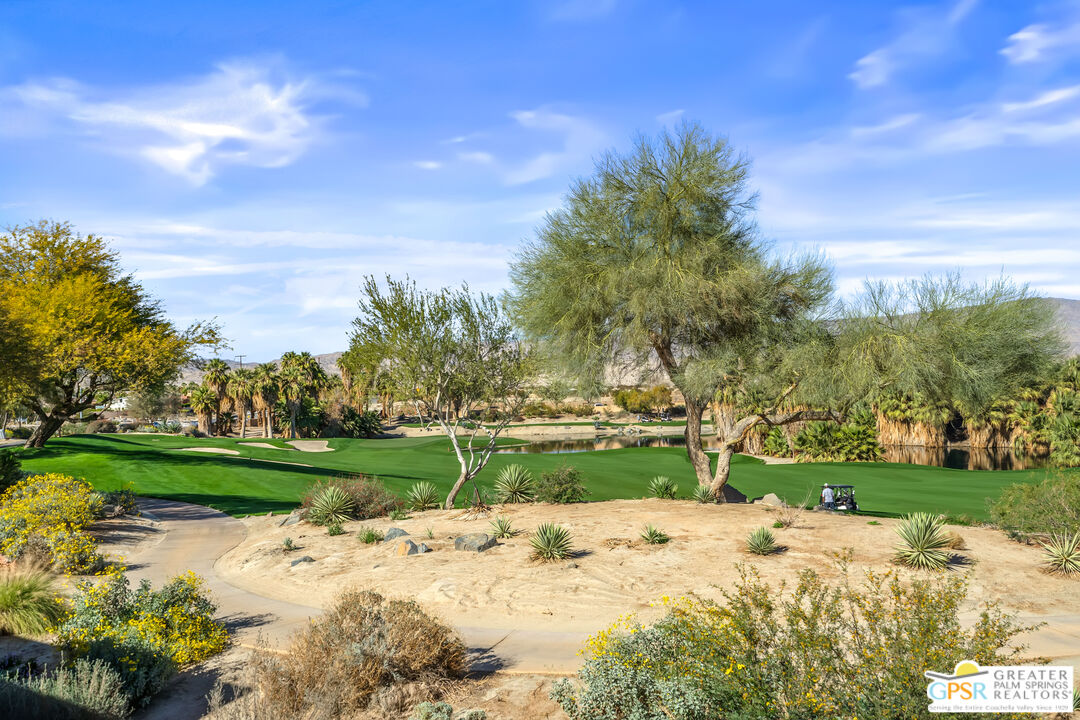 204 Retreat Circle Palm Desert, CA 92260 - Photo 5 of 60 a view of a park with large trees and a wooden fence
