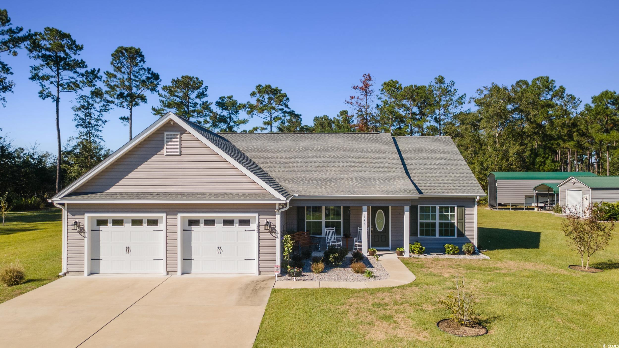 View of front of house featuring a porch, a front lawn, roof with shingles, and concrete driveway
