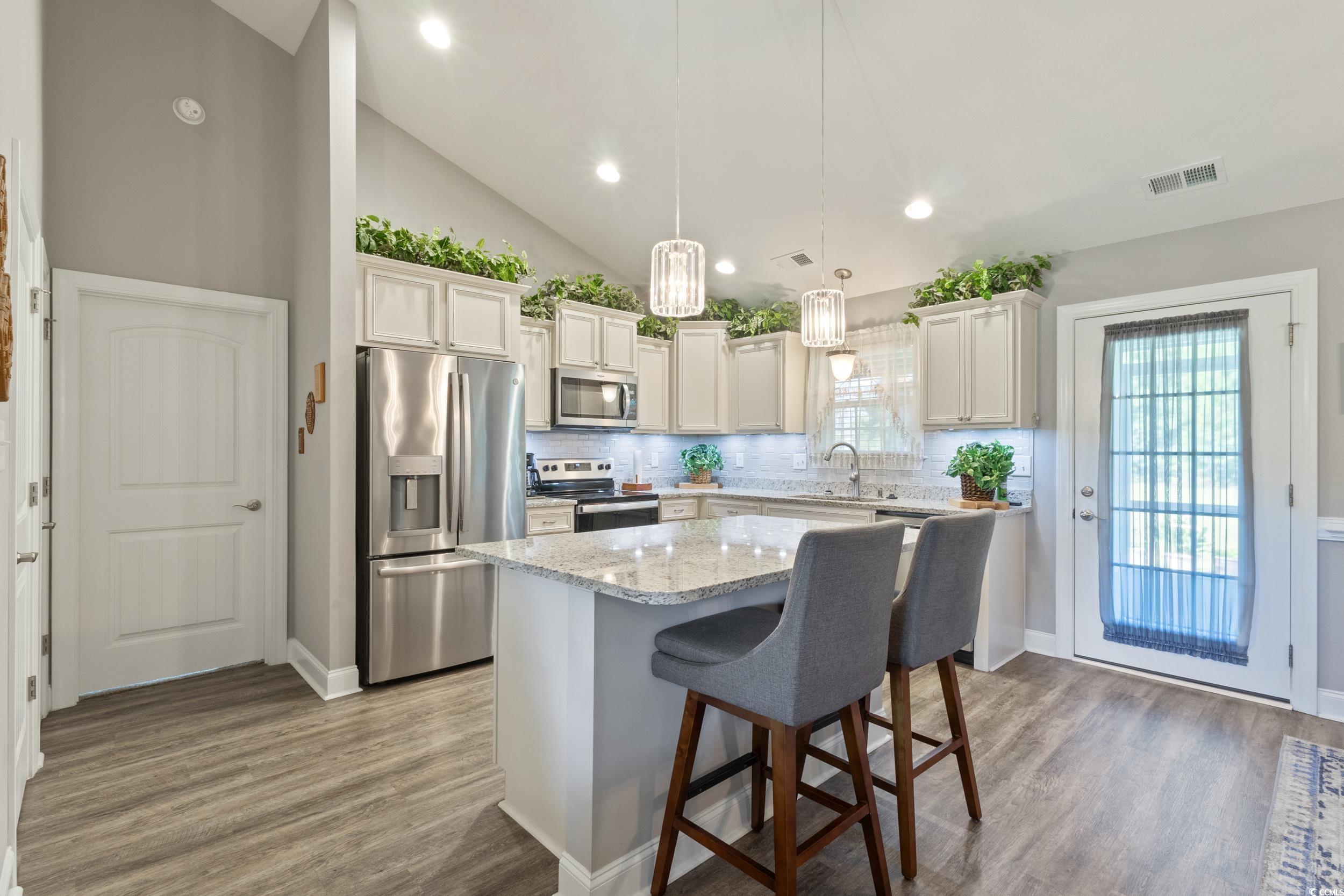 1353 Hucks Road Aynor, SC 29511 - Photo 16 of 40 Kitchen with appliances with stainless steel finishes, decorative backsplash, a breakfast bar area, pendant lighting, and light stone countertops