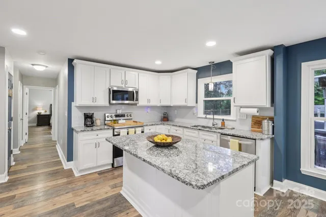 a kitchen with stainless steel appliances granite countertop living room and chairs