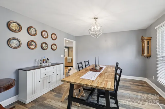 a large kitchen with granite countertop a stove a sink a refrigerator and white cabinets with wooden floor