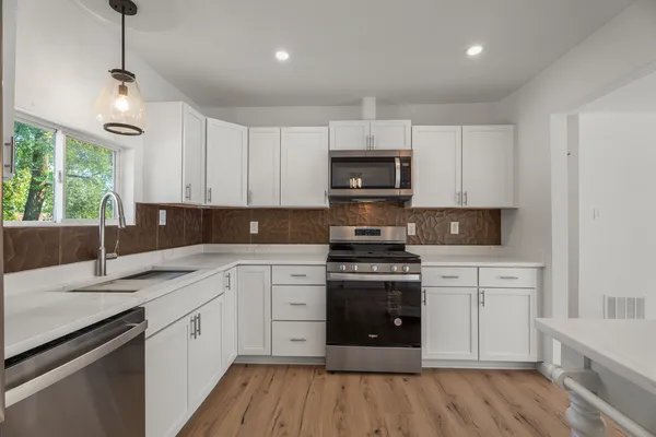 a kitchen with stainless steel appliances granite countertop a stove a sink and a microwave