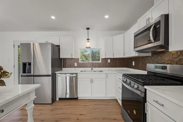 a kitchen with stainless steel appliances a stove a sink cabinets and a wooden floor