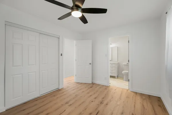 an empty room with wooden floor a ceiling fan and windows