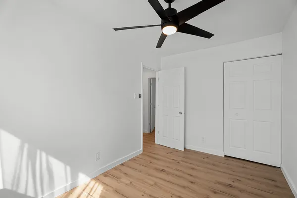 a view of empty room with wooden floor and fan