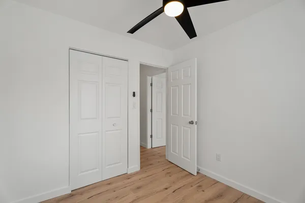 an empty room with wooden floor cabinet and windows