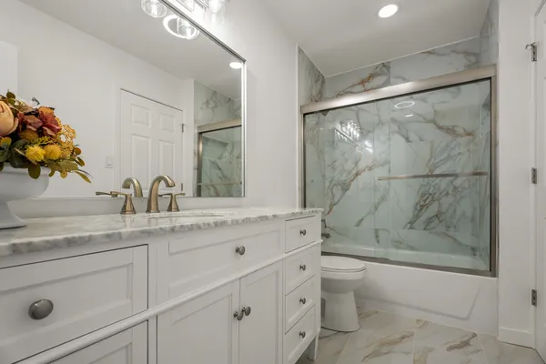 a bathroom with a granite countertop sink a toilet and shower