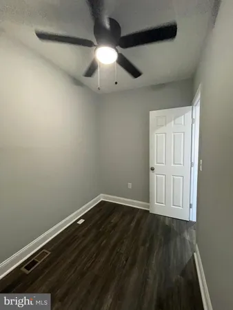 an empty room with wooden floor cabinet and windows