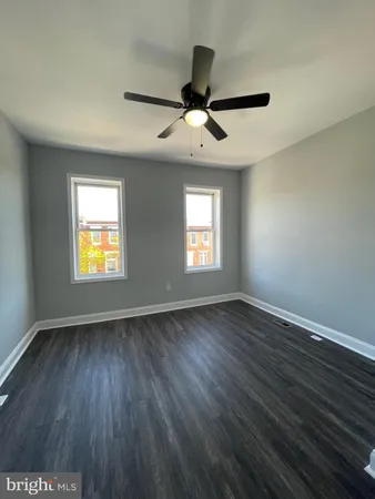 an empty room with wooden floor ceiling fan and windows