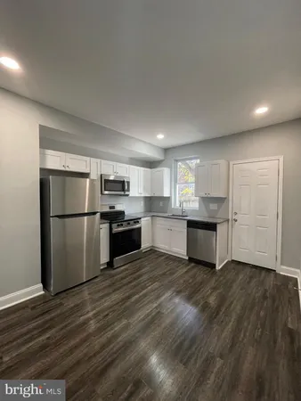 a kitchen with stainless steel appliances granite countertop a refrigerator sink and white cabinets