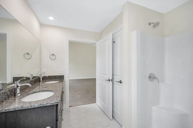 a bathroom with a granite countertop sink a mirror and shower
