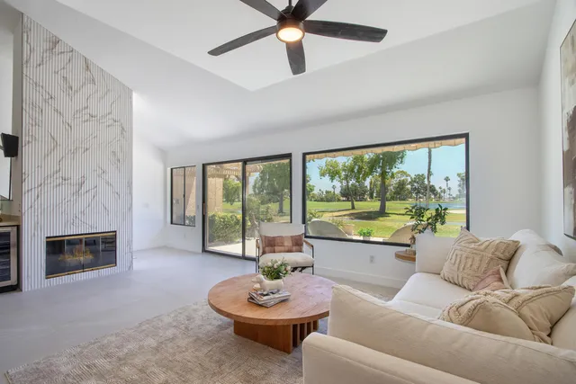 a kitchen with stainless steel appliances granite countertop a sink a stove a dining table chairs and view living room