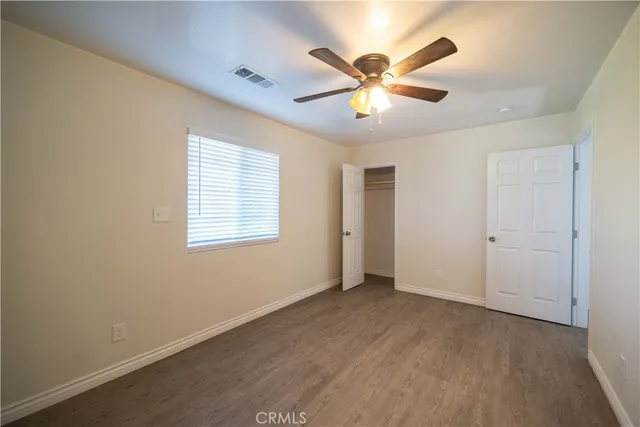 an empty room with wooden floor fan and windows