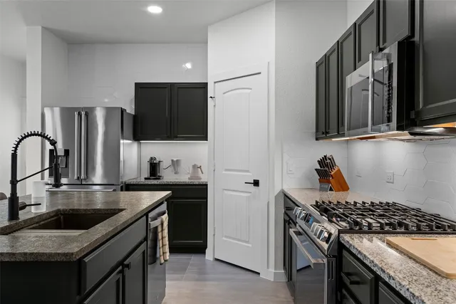 a kitchen with kitchen island granite countertop a sink stainless steel appliances and cabinets