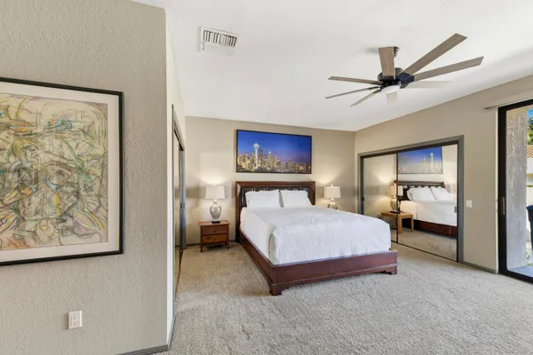 a spacious bedroom with a bed and a painting on the wall