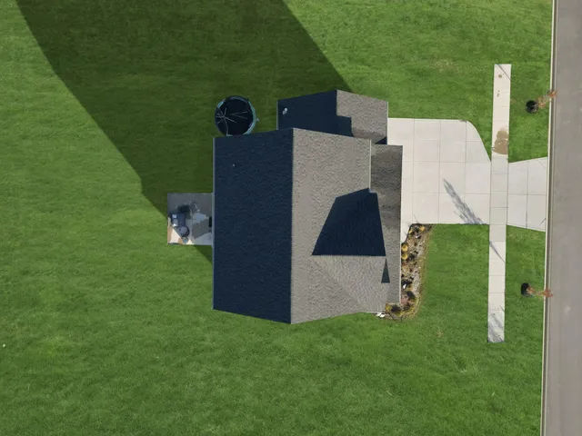 an aerial view of a residential houses with outdoor space and trees