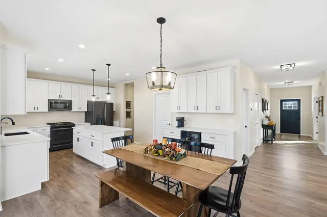 a kitchen with stainless steel appliances kitchen island granite countertop a dining table chairs stove refrigerator and cabinets