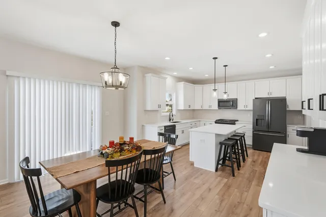 a view of a dining room and livingroom with furniture wooden floor a chandelier
