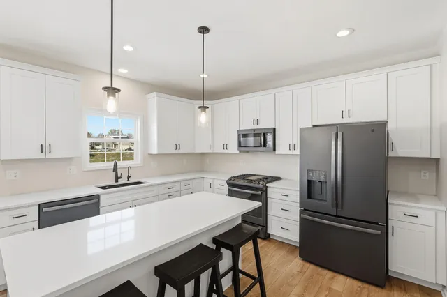 a kitchen with stainless steel appliances a sink a stove a refrigerator a center island and cabinets