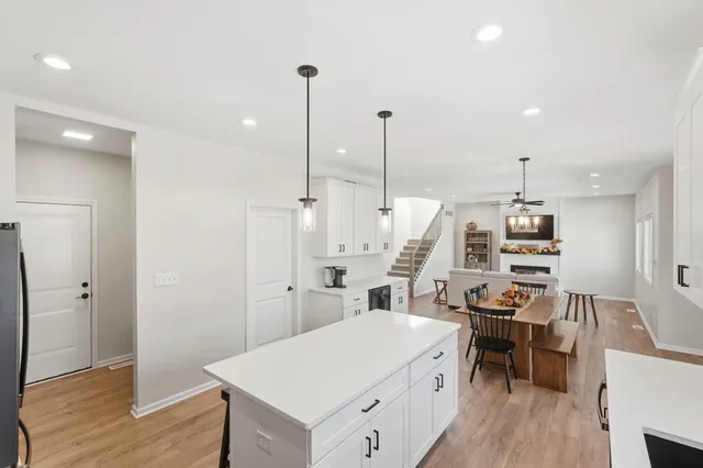 a kitchen with a sink a stove a refrigerator and white cabinets with wooden floor
