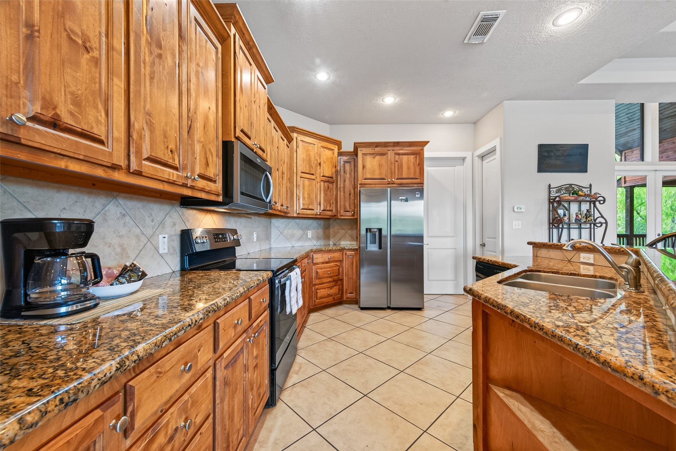 8 Smith Loop South Cleveland, TX 77327 - Photo 10 of 29 Spacious kitchen with rich wood cabinetry, granite countertops, and stainless steel appliances, offering ample storage and a warm, inviting atmosphere.