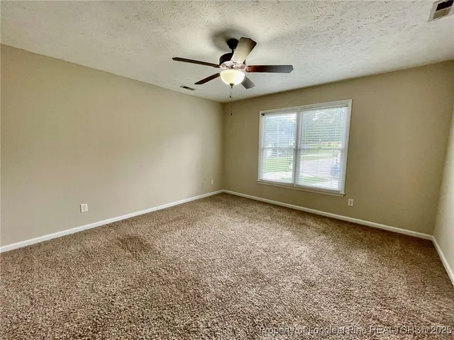 an empty room with a window and a ceiling fan