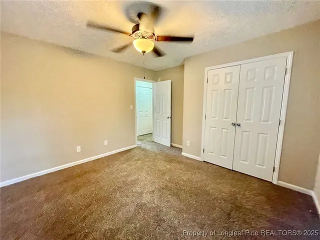 an empty room with a chandelier fan and windows