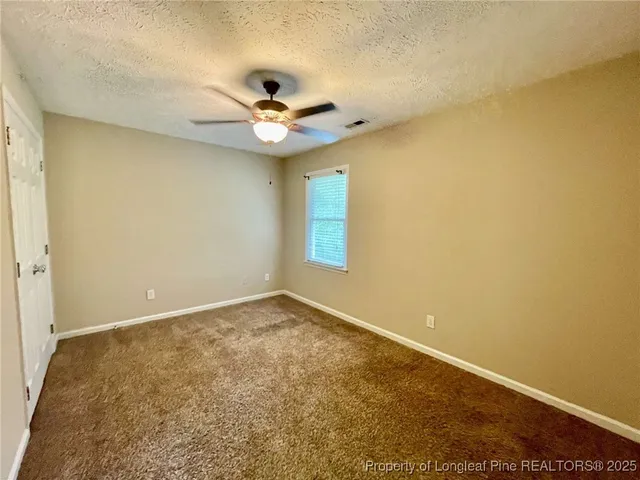 an empty room with a window and a ceiling fan