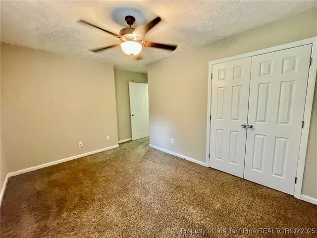 an empty room with a chandelier fan and closet