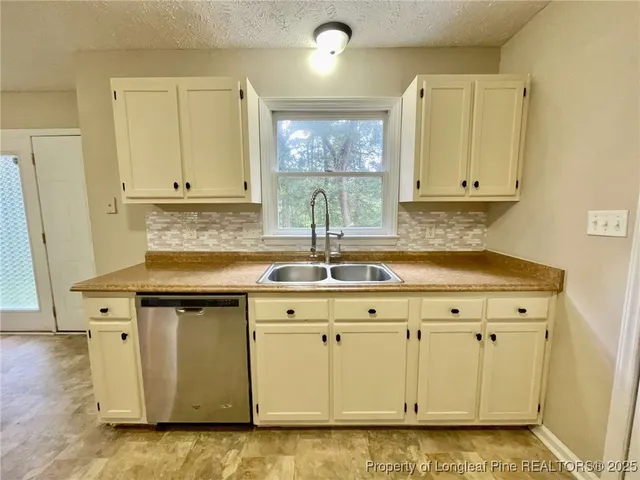 a kitchen with granite countertop a sink white cabinets and a stove