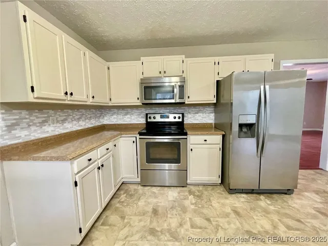 a kitchen with white cabinets and stainless steel appliances