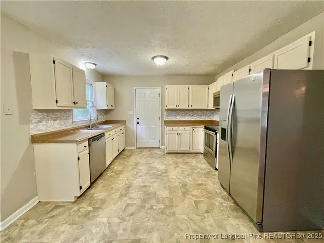 a kitchen with stainless steel appliances granite countertop a refrigerator sink and cabinets