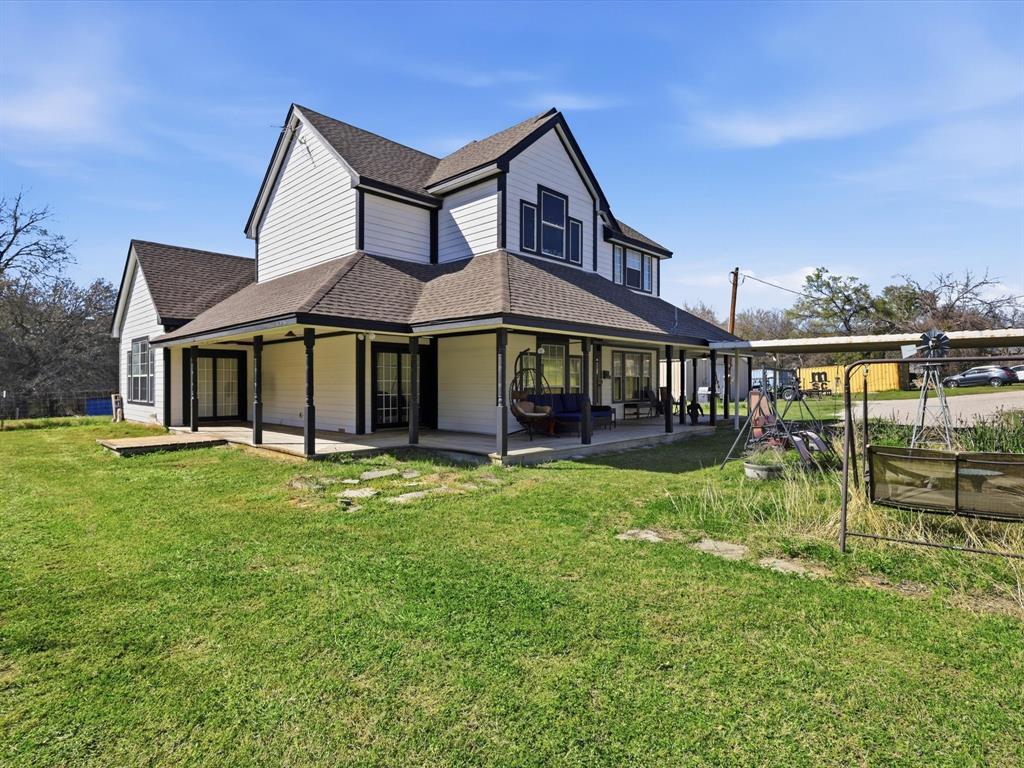 130 Parsonage Street Azle, TX 76020 - Photo 35 of 39 Rear view of house featuring a shingled roof, a yard, and a patio