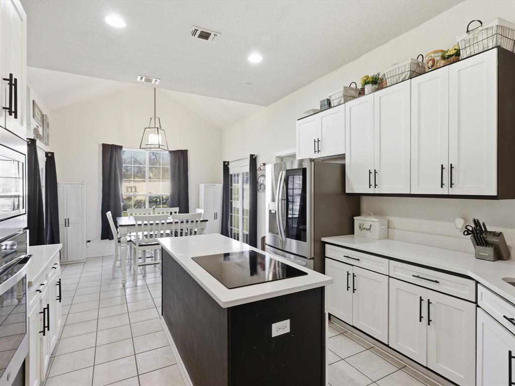 130 Parsonage Street Azle, TX 76020 - Photo 5 of 39 Kitchen with a kitchen island, stainless steel appliances, vaulted ceiling, dual tone cabinetry, and light tile patterned floors