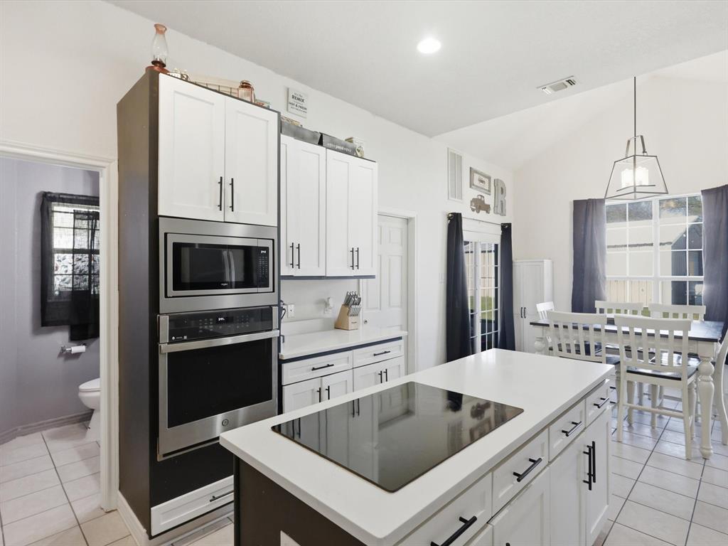 130 Parsonage Street Azle, TX 76020 - Photo 6 of 39 Kitchen with light tile patterned floors, white cabinetry, stainless steel appliances, a kitchen island, and vaulted ceiling