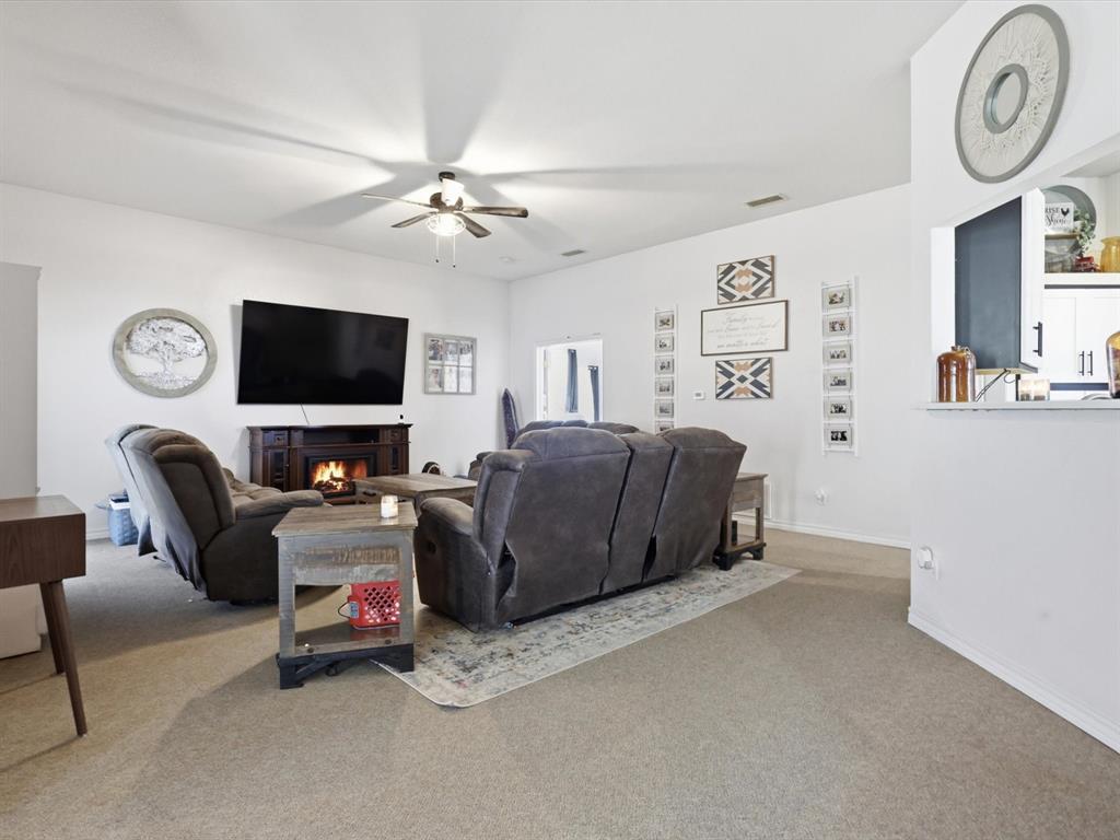 130 Parsonage Street Azle, TX 76020 - Photo 10 of 39 Carpeted living room with a warm lit fireplace and a ceiling fan