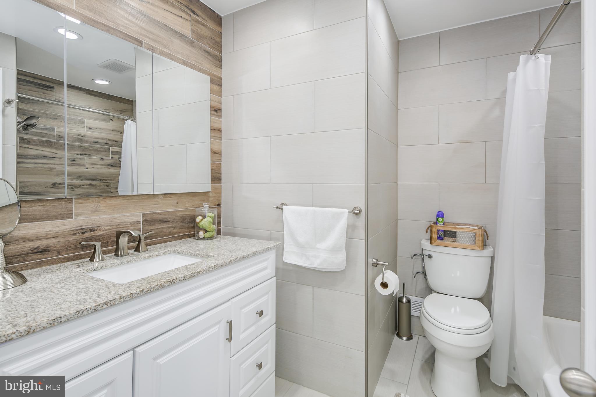 136 Claybrook Drive Silver Spring, MD 20902 - Photo 16 of 30 a bathroom with a granite countertop sink a toilet and a mirror