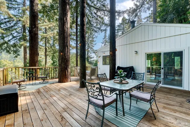 a view of a patio with a dining table and chairs with wooden floor and fence