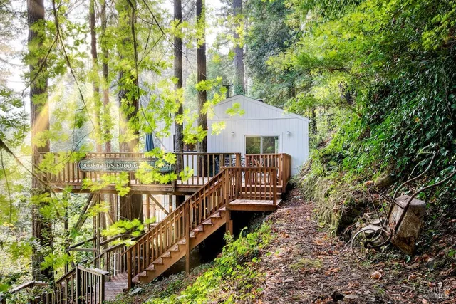 a view of a house with large trees and wooden fence