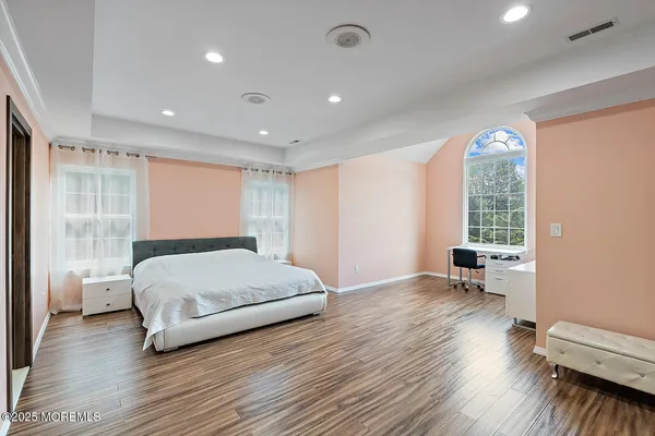 a spacious bedroom with a large bed and a wooden floor