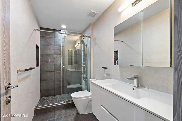 a bathroom with a shower sink vanity mirror and toilet