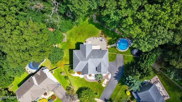 an aerial view of a house with swimming pool a yard and a large tree