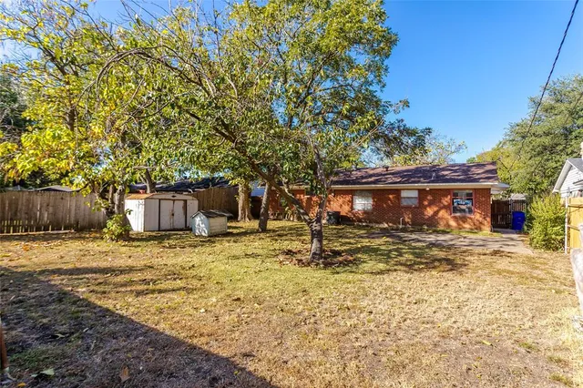 a view of a backyard with wooden fence and a large tree