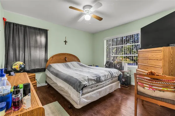 a bedroom with a bed and dresser with wooden floor