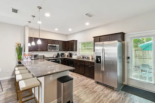 a kitchen with granite countertop a refrigerator a stove a sink a dining table and chairs